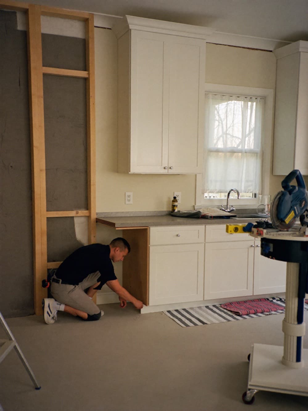 Remodeling contractor checking a cabinet base with a level in a kitchen mid-renovation